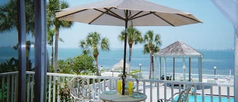 view of private beach, water, pool/hot tub from living room/ dining room