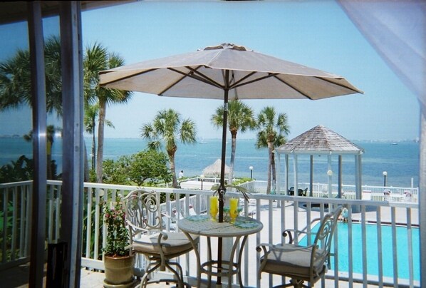 view of private beach, water, pool/hot tub from living room/ dining room