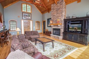 Spacious Living Area with Open Floor Plan, Stacked Stone Fireplace, and Large HDTV