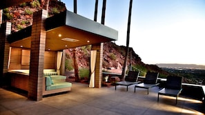 Twilight patio with modern cabana, mountain views, and cozy lighting.