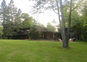 Front of lodge, with expansive lawn, large screened-in porch, patio and fire pit