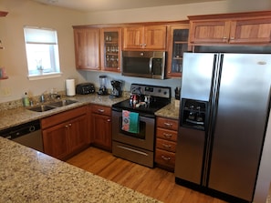 Bright, clean, fully equipped kitchen with a breakfast bar with 4 stools