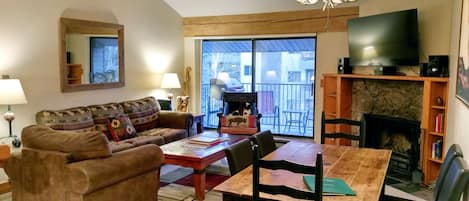 Living room with sofa bed, wood fireplace, dining table, and balcony w/ gas BBQ