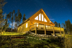 Bear Crossing Cabin lit up at night with custom cedar bench and large deck