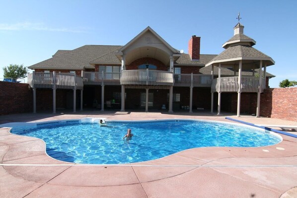 Pool area with 8 foot brick privacy wall, fireplace and fire pit.