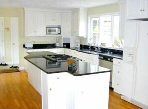 Gourmet kitchen with custom cabnitry and granite, opens to dining, FR, and decks
