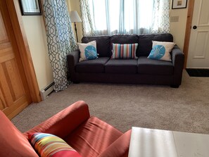 Comfy living room, light-filled showing couch, arm chair, side tables.