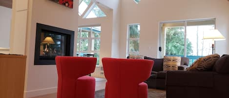 living room has vaulted cedar plank ceilings and opens to a covered balcony