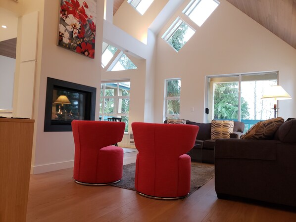 living room has vaulted cedar plank ceilings and opens to a covered balcony