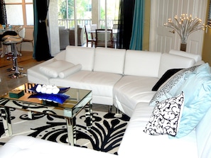 The great room with large white leather sectional couch with a lanai view