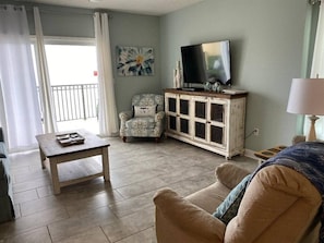 Living room features glass sliding doors leading to balcony with beachfront ocean views.