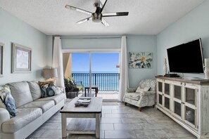 Living room features glass sliding doors leading to balcony, sleeper sofa & 2 recliners