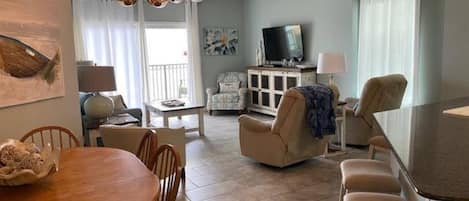 Living room features glass sliding doors leading to balcony with beachfront ocean views.