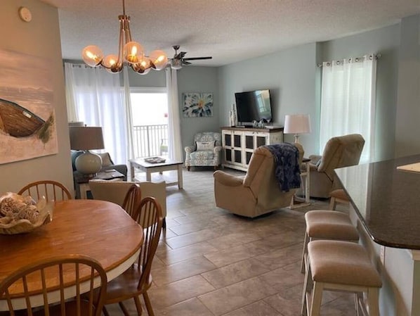 Living room features glass sliding doors leading to balcony with beachfront ocean views.