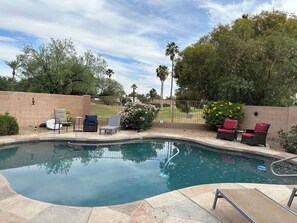 Heated pool surrounded by comfortable lounges and chairs.