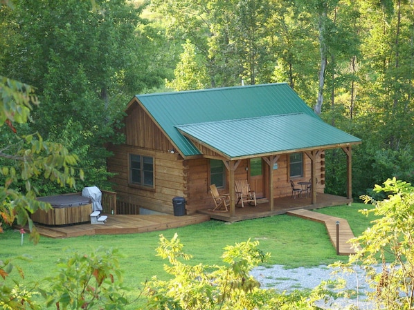 View of our Lazy Creek Cabin nestled in the woods with the creek behind it.