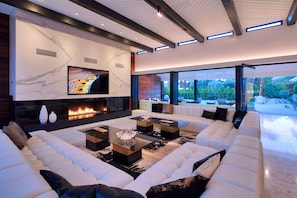 Huge great room with 18' custom sofa, marble fireplace, 80'" TV, overlooks pool.