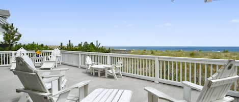 Large oceanfront deck with Adirondack chairs overlooks a beautiful dune  & beach