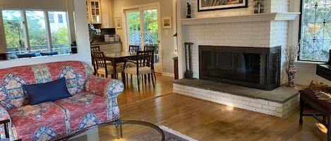 Partial view of living room, fireplace, dining area.