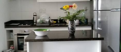 Kitchen, with granite island, appliances and range-hood. 