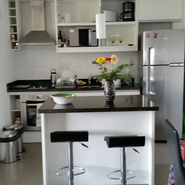 Kitchen, with granite island, appliances and range-hood. 