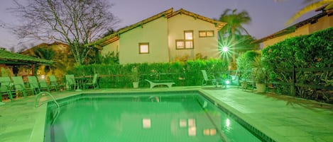 piscina e fachada lateral da casa à noite