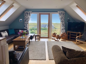 Living room and balcony overlooking Atlantic Ocean and community of Kilchattan 