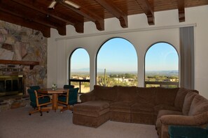 Main gathering room with flat screen TV, fireplace, couch and view of city.