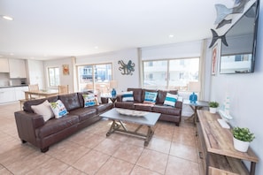 The main living area includes a sofa set, cable TV, and sliding glass doors that open up to the expansive front patio.