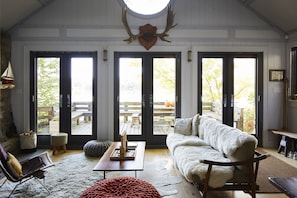 Main Cottage living room. View to deck, table, and the lake.