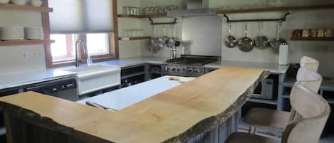 The kitchen with granite countertops and natural wood bar with seating.