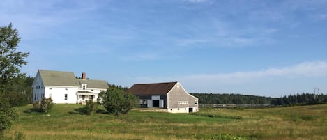 View of house, barn, fields and water from  road