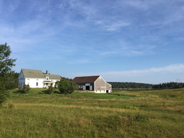 View of house, barn, fields and water from  road