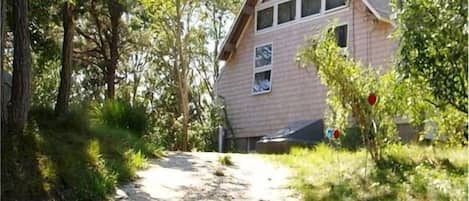 Side view house seashell driveway. To the left is a cobble stone path