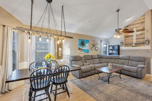 Living Room: farmhouse table, ladder light, large couch, ceiling fan, TV & more.