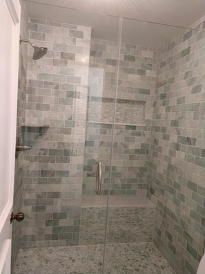 Newly renovated master shower with tumbled marble, large seat and frameless door