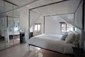 The airy bedroom has a canopy bed, reading lights, and lots of storage