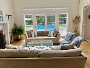 Living room w/sliding doors out to private backyard, deck, brick patio & pool