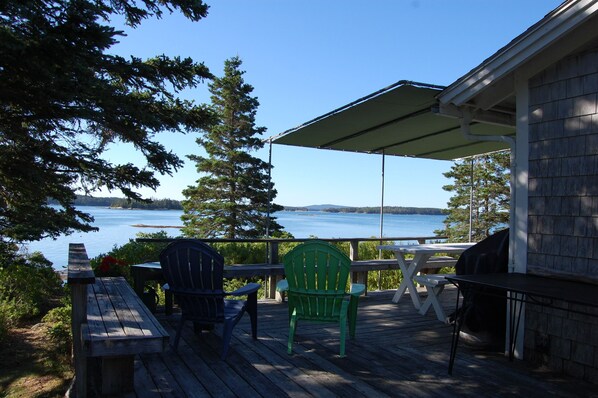 Wraparound porch with Adirondack chairs, picnic table, and grill