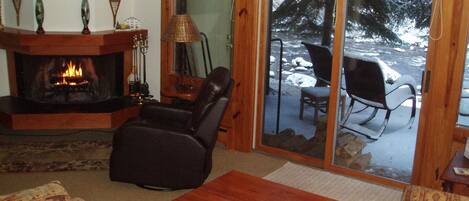 Cozy sunken den with wood-burning fireplace after an early winter snow.