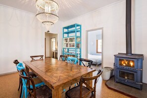 Gather around the large wooden dining table beneath elegant chandeliers, with a wood fire setting the perfect ambiance for family meals.