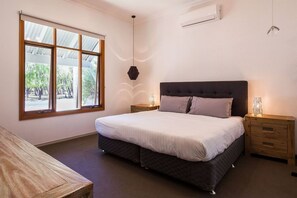 The first bedroom is a peaceful retreat with a king bed, large windows, and air conditioning for ultimate comfort.