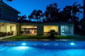 Pool, outside living and dining area at night