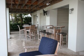 covered seating area by pool for eating, hanging out, grilling, watching TV