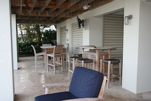 covered seating area by pool for eating, hanging out, grilling, watching TV