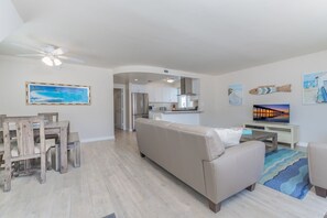 Vantage point from the unit's entry area toward kitchen, living room and TV. Wood-look tile flooring throughout updated living areas.
                