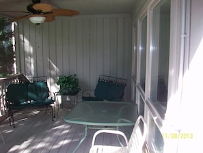 Large shaded screened In porch with ceiling fan.