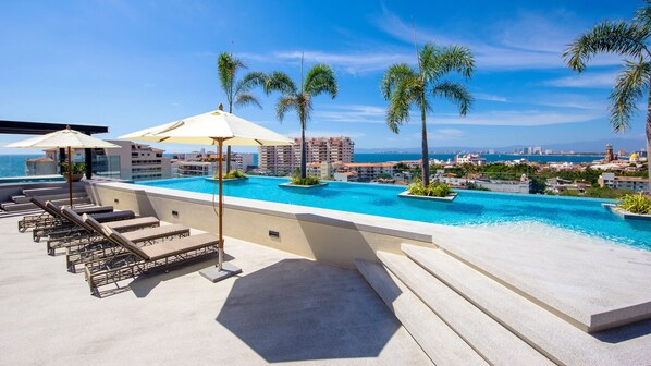 Pool and view out to ocean. Lounge chairs for sun. Jacuzzi on far left