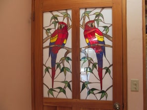 Inside entrance Teak door with stained glass scarlet Macaws by local artist