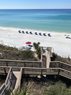 Private beach at the bottom of steps with 2 chairs and an umbrella set up.